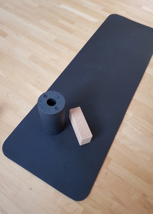 Auf unserem Holzfußboden liegt meine schwarze Yogamatte.